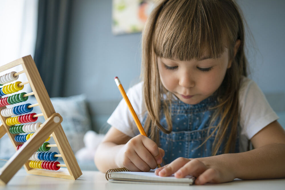 Young girl writing with a pencil in a notebook